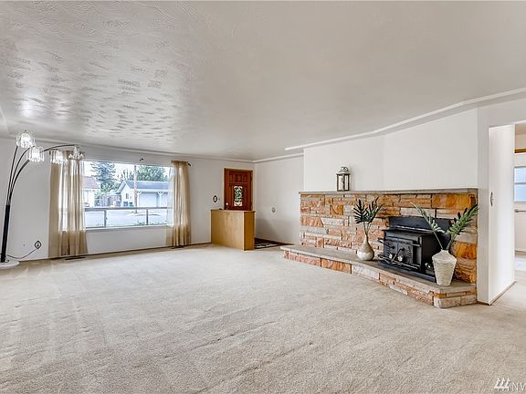 Enter to an oversized living area accented with a fireplace insert with a warm stone surround and plush carpeting.