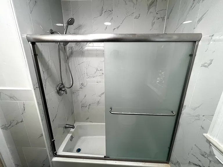 The new bathroom features a glass sliding door that is clouded for privacy and a brand new tub and shower!