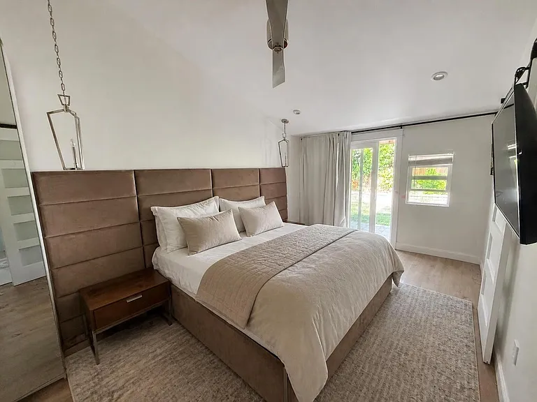 Mater bedroom with door to back yard and small window, vaulted ceilings.