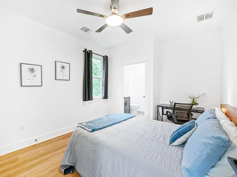 Well-sized bedroom with hardwood floors, ceiling fan, and a dedicated desk area, plus convenient access to the bathroom.