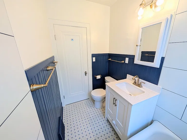 Remodeled bathroom. New security glass window with vent, new shower tile and fixtures, new vanity, new toilet, new champagne gold accents