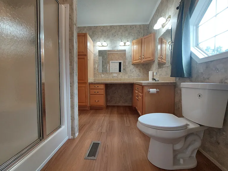 Back bathroom looking toward door from closet, showing 4' x 3' shower, toilet, sink and countertop. GFI outlet has USB A and C ports for phone charging. Note bright, octagon window!