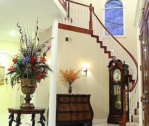 Gorgeous foyer features marble flooring, soaring ceilings, custom moldings, and double front doors.