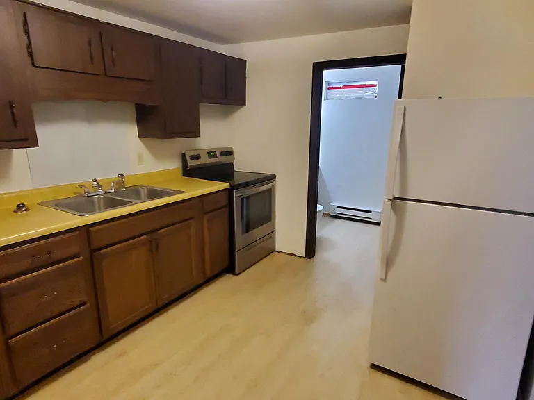 Kitchen with double sinks, electric oven and refrigerator.