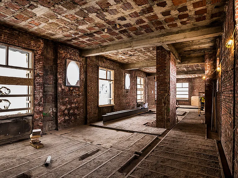 Before: Room featuring exposed brick and wood plank flooring during renovation