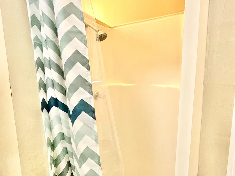 shower with a curtain rod and showerhead, offering a simple, functional space for daily use.