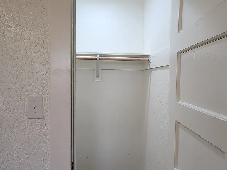 Front bedroom lighted closet with clothes bar and shelf.