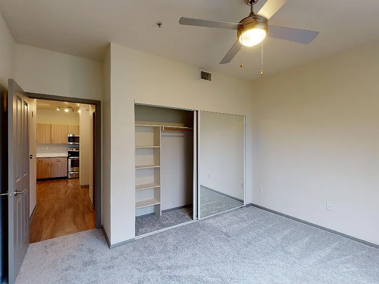 Spacious apartment bedroom with plush carpet flooring.