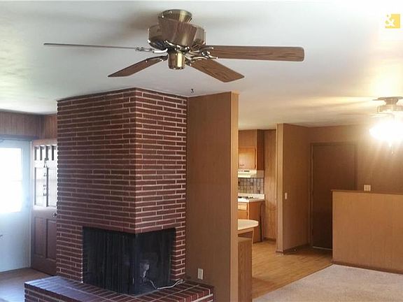 Corner fireplace in the living room, shows the dining room with the half wall for the stairs to the basement.