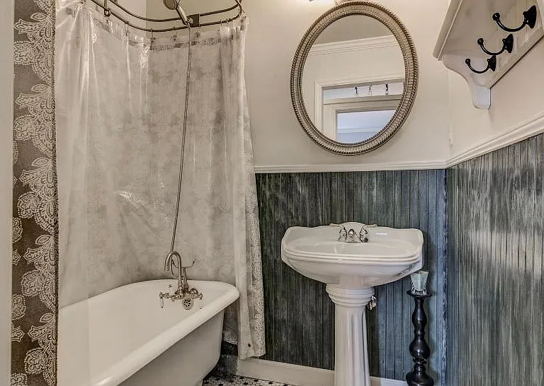Claw foot cast iron tub and pedestal sink with separate toilet area for main bedroom