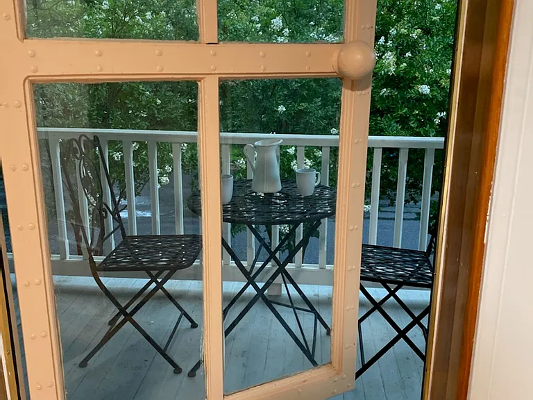 Balcony door in upstairs east bedroom leads to the bistro setting with a beautiful view of the front street and trees.