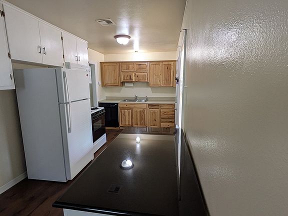 Kitchen with granite-topped island, refrigerator, stove, microwave, double sink with sprayer, and laundry hookups.