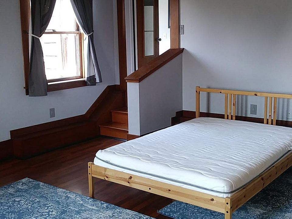Main Room - full-size bed as seen from entry. Laminate flooring, area rugs. Window in NE corner.