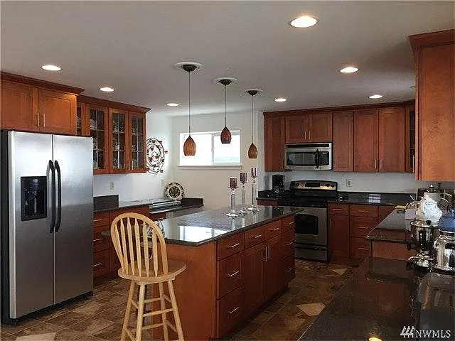Spacious kitchen with large, long island, tons of storage, and two built in granite top desks with cabinets