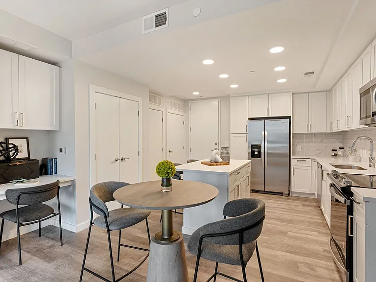 Gourmet Kitchen And Dining Area With White Countertops, Pearl Paneled Cabinets, and Stainless-Steel Appliances