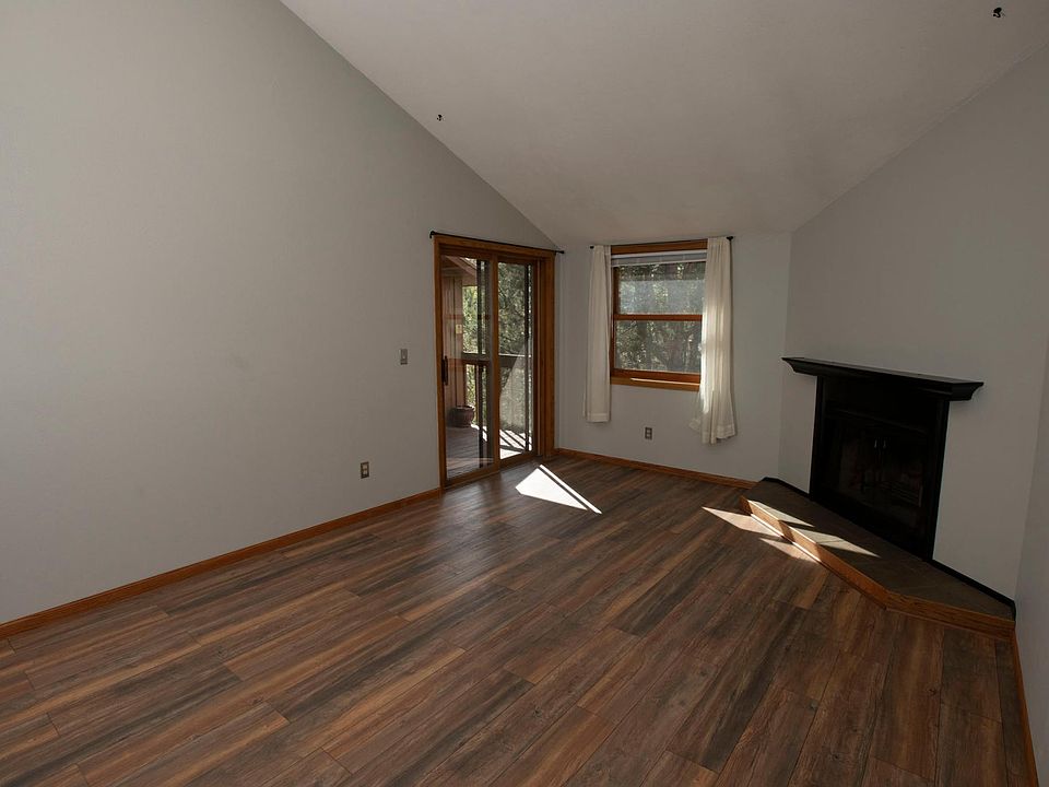 Living room with vaulted ceiling, electric fireplace and view to quiet green space outside