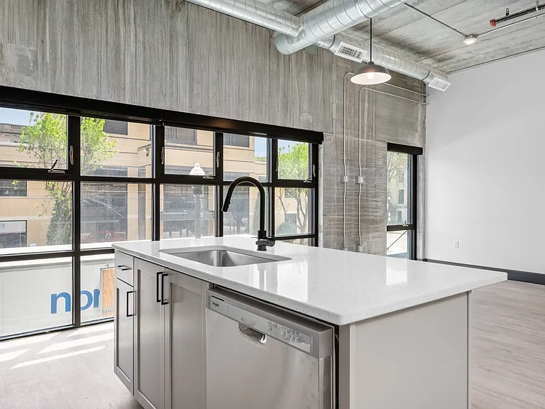 Modern industrial apartment kitchen with stunning floor-to-ceiling windows, sleek countertops, and stainless steel appliances. Modern industrial apartment kitchen with stunning floor-to-ceiling windows, sleek countertops, and stainless steel appliances.