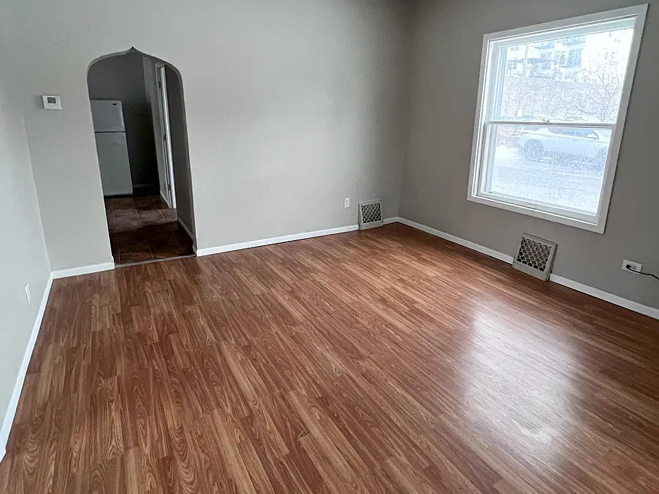 Living room with large windows and vinyl flooring.