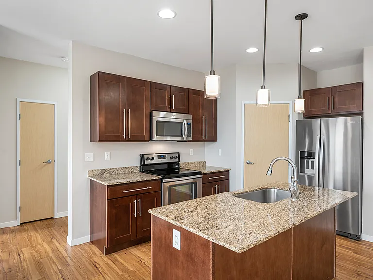 Modern kitchen with granite countertops, stainless steel appliances, and elegant pendant lighting. Modern kitchen with granite countertops, stainless steel appliances, and elegant pendant lighting.