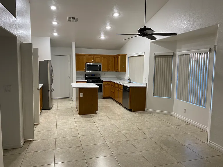 View of the kitchen from the family room. Very open concept. Pot shelves throughout for decor. Oversized porcelain tile. Ceiling fans throughout the home.