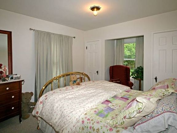 This bedroom has an extended window area that is perfect for a bedroom chair.