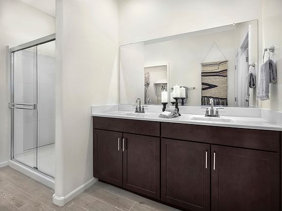 The primary bathroom boasts dual sinks and a walk-in shower.