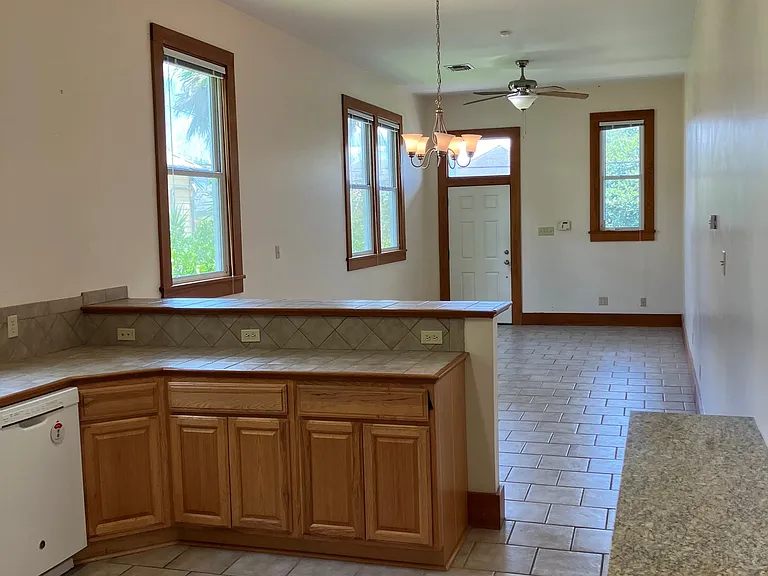 View from kitchen to dining area, living room front door. Note the extra granite topped cabinet