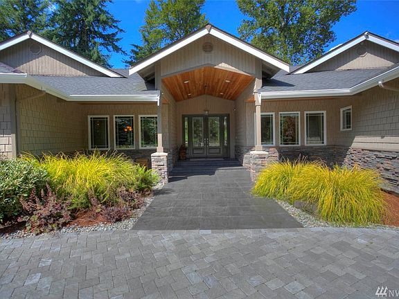 Exquisite tile entry with deep overhang porch featuring tongue & groove cedar. The wide glass double doors create a feeling of warmth and welcome. 