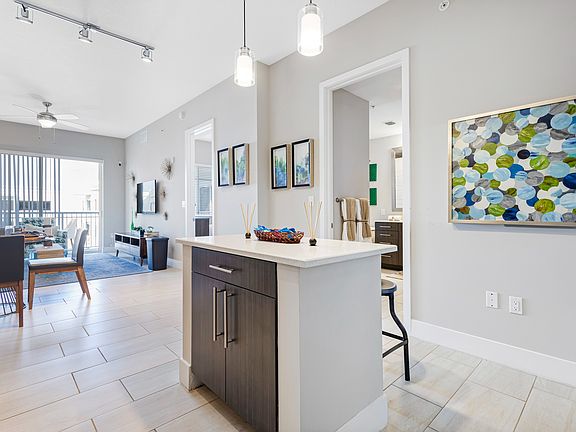 Model kitchen and dining room at our apartments in Boca Raton, featuring chairs around a table and counter seating.