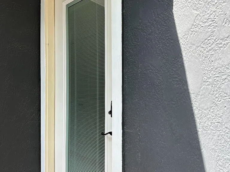 Door at the top of the exterior stairs leading to upper level; double-pane door with integrated blinds for adjustable privacy and light control.