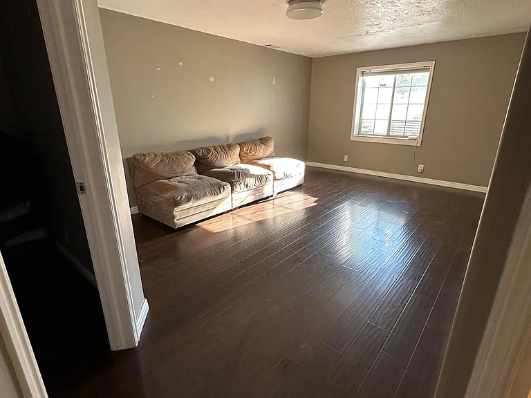 Large, bright living area with Pergo flooring. Modular sofas work best for stairwell. Unfurnished (sofa pictured is previous tenants).