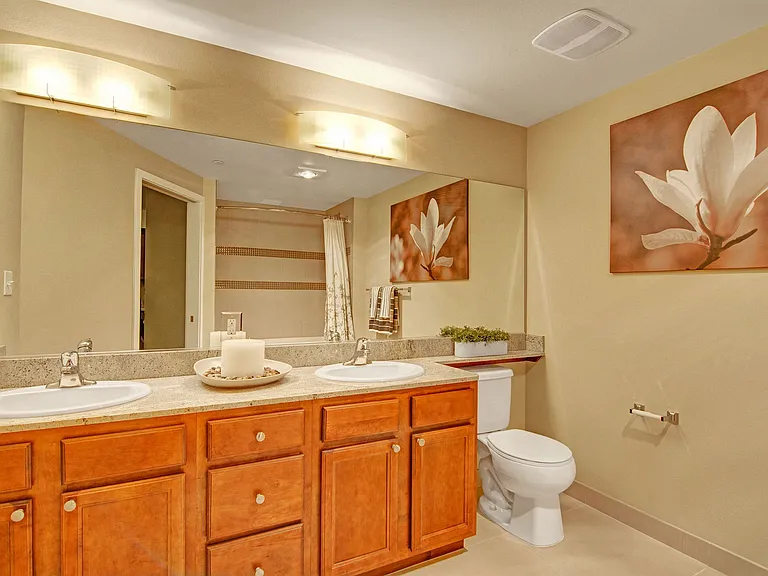 A large bathroom with double sinks, a shower, and a wide mirror above the sinks
