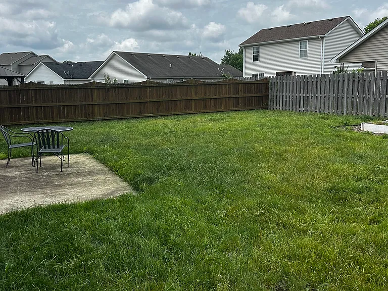 Back yard, patio, tables and 2 chairs.