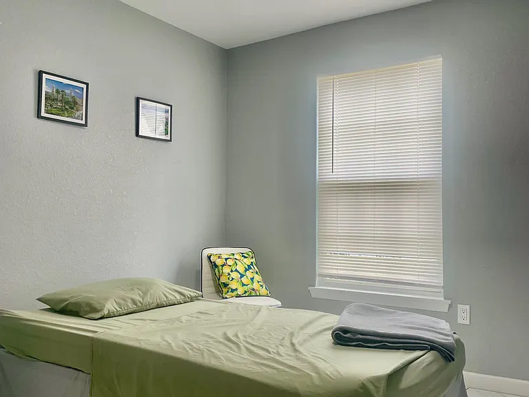Furnished bedroom with a comfortable bed, window with blinds, and neutral finishes for an easy move-in setup.