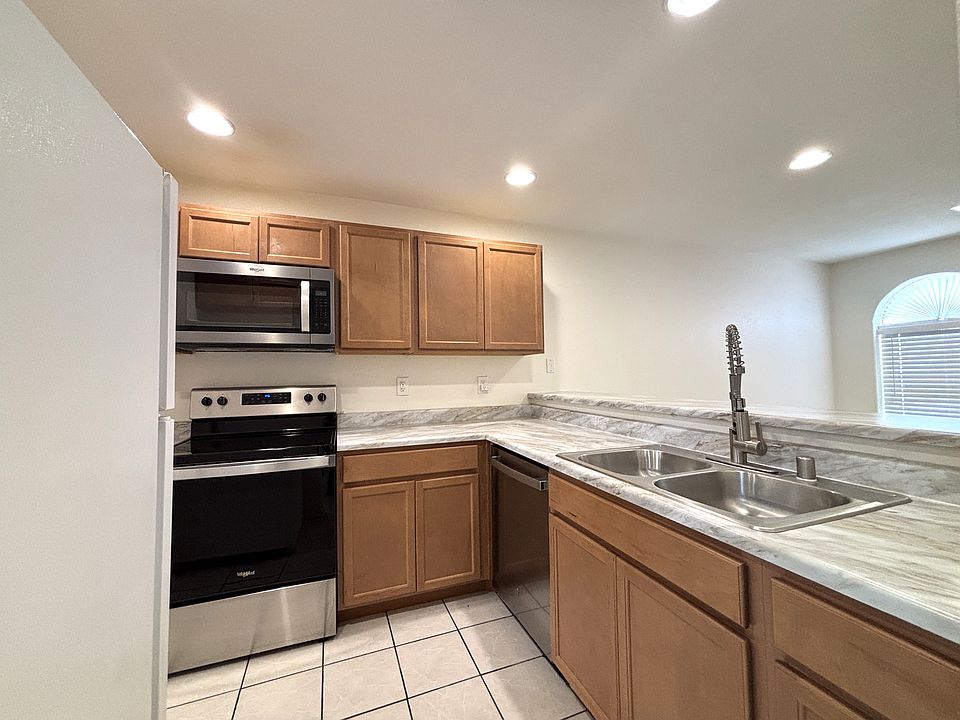 Large open modern kitchen with stainless steel appliances & sink, tiled floor, recessed LED lighting with dimmers, wood cabinets...