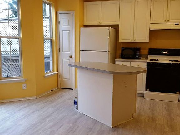 Large sunny kitchen with white cabinets and new floor.