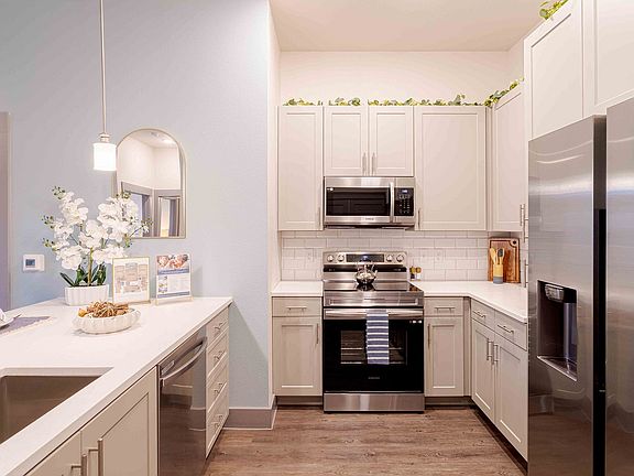 Modern apartment kitchen featuring stainless steel appliances, white cabinetry, and stylish finishes.