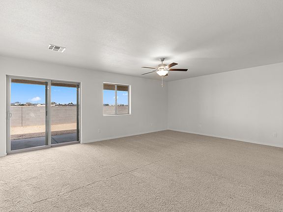 Expansive living room with a ceiling fan and sliding glass back doors.