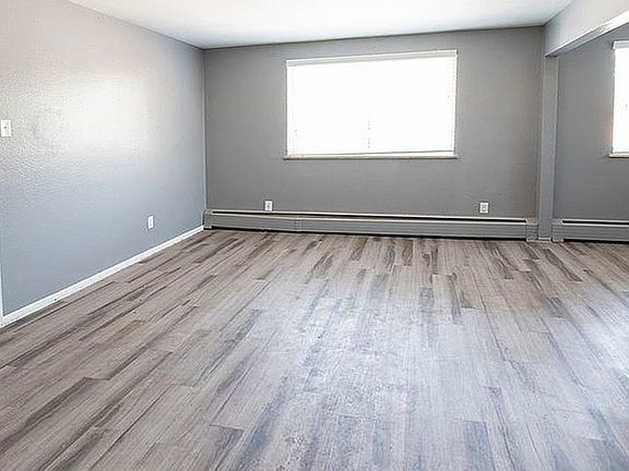 Bright and spacious living area with sleek gray flooring and modern neutral walls, perfect for stylish urban living.