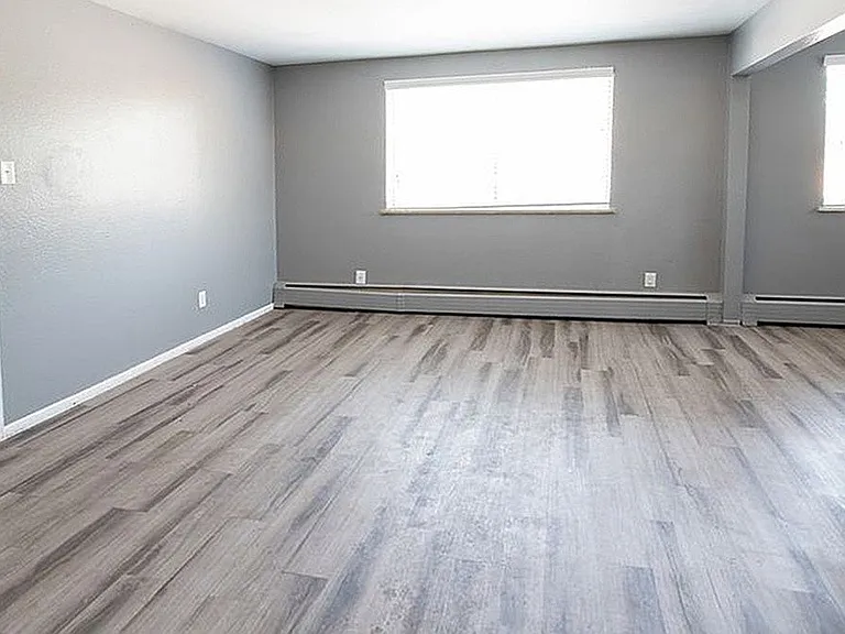 Bright and spacious living area with sleek gray flooring and modern neutral walls, perfect for stylish urban living.