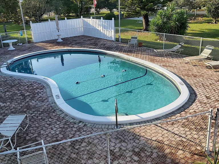 Heated swimming pool with chairs and tables.