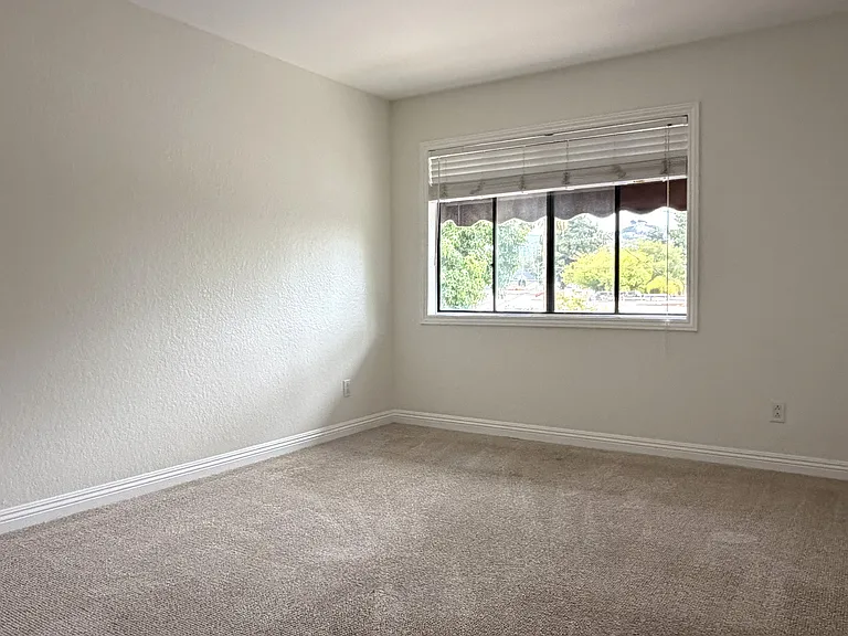 Second bedroom with carpet, window, and flexible layout potential.