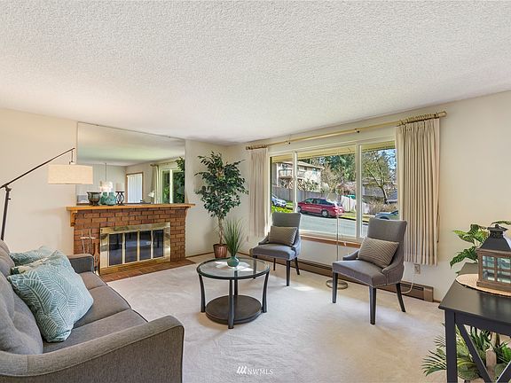 Formal living room has southern exposure and is graced with an elegant wood burning brick fireplace. Carpeting is covering up beautiful, real hardwood floors.