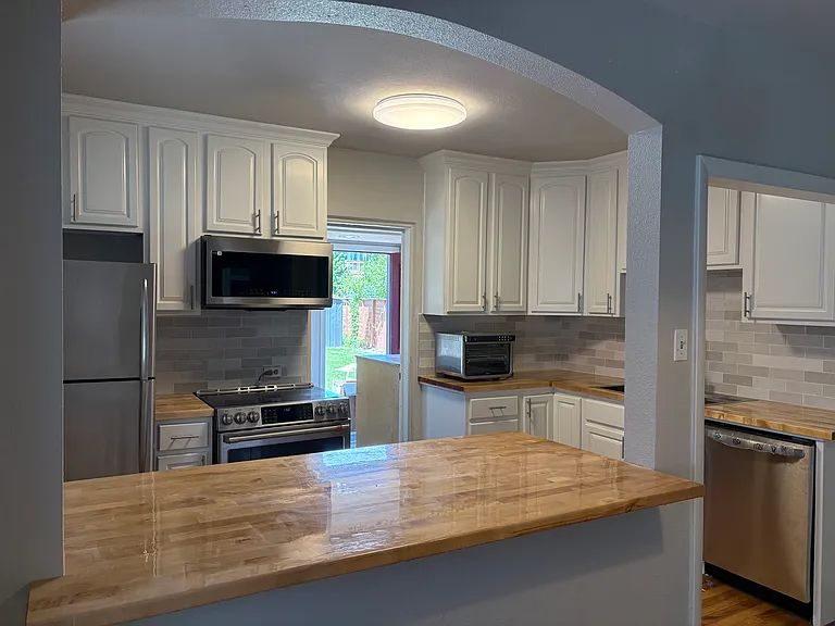 view kitchen from dining area. peaks of the back yard through the laundry room