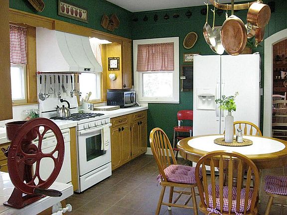 Country kitchen with several windows, white tile counters, gas range, dishwasher, antique farm sink,