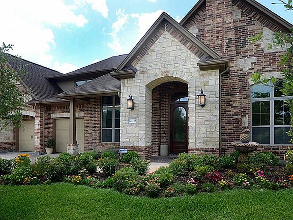 A meandering walkway leads past colorful, professional landscaping to the covered front Porch that i