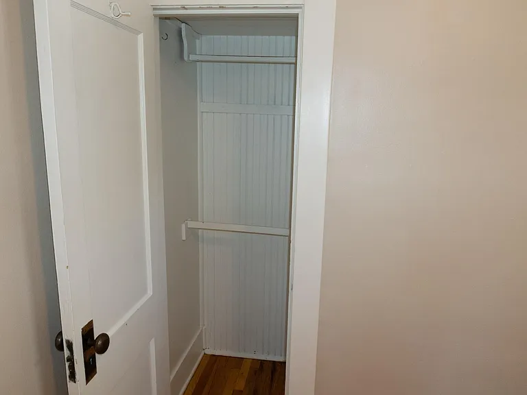 Closet in the front bedroom has two clothes rack bars, and high shelf above those.