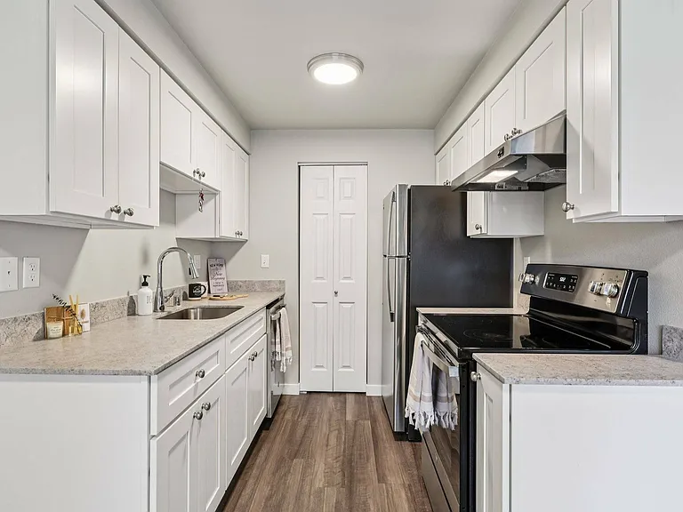 Bright, open-concept kitchen with stainless steel refrigerator and oven at Foster Creek Apartments, Tukwila.