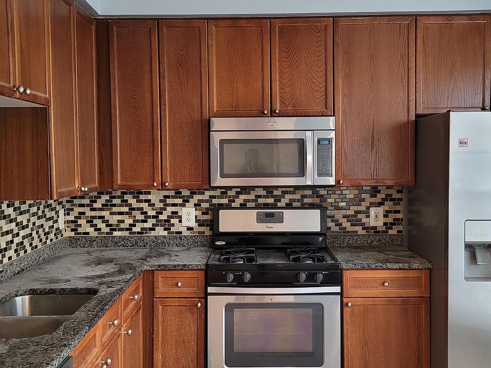 Kitchen with all Stainless appliances, Gas stove and full size microwave with granite counter top and tiled backsplash
