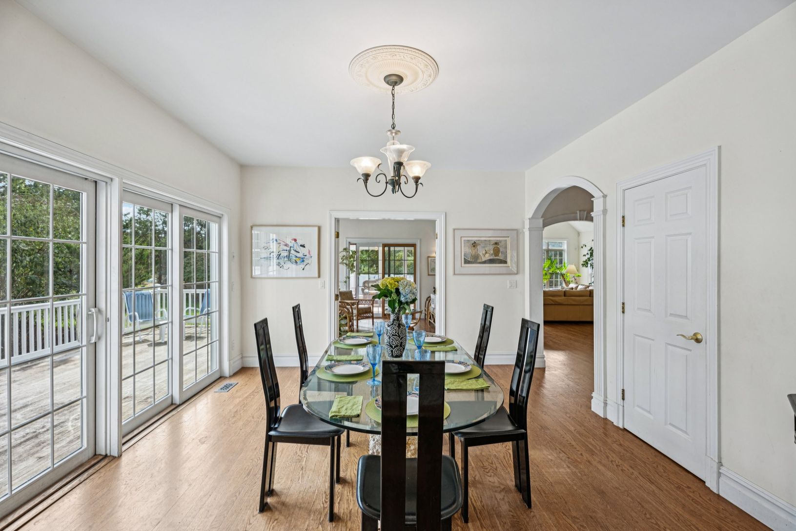 An inviting dining area showcasing graceful arched walkways, oak flooring, and a stunning chandelier